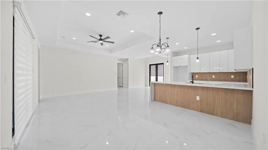 Kitchen featuring white cabinetry, modern cabinets, open floor plan, a chandelier, and pendant lighting