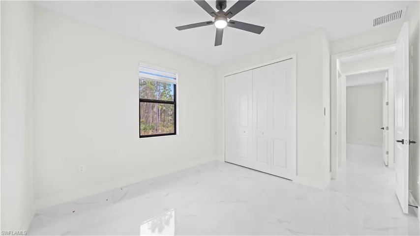 Unfurnished bedroom featuring light marble finish flooring, a closet, and a ceiling fan