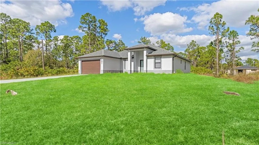 Prairie-style house with a front yard, an attached garage, stucco siding, and a shingled roof