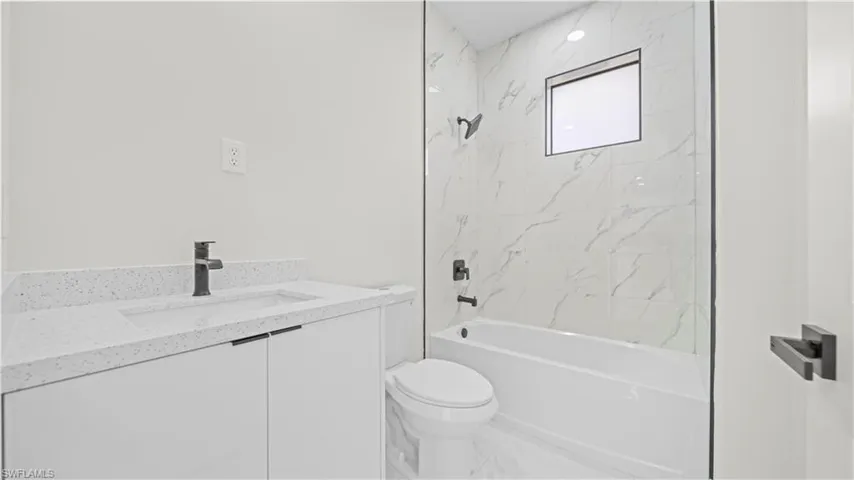 Bathroom with vanity, washtub / shower combination, and marble finish floors