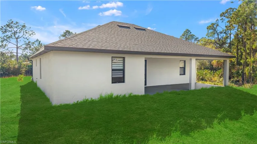 Back of house with a shingled roof, a lawn, stucco siding, and a patio