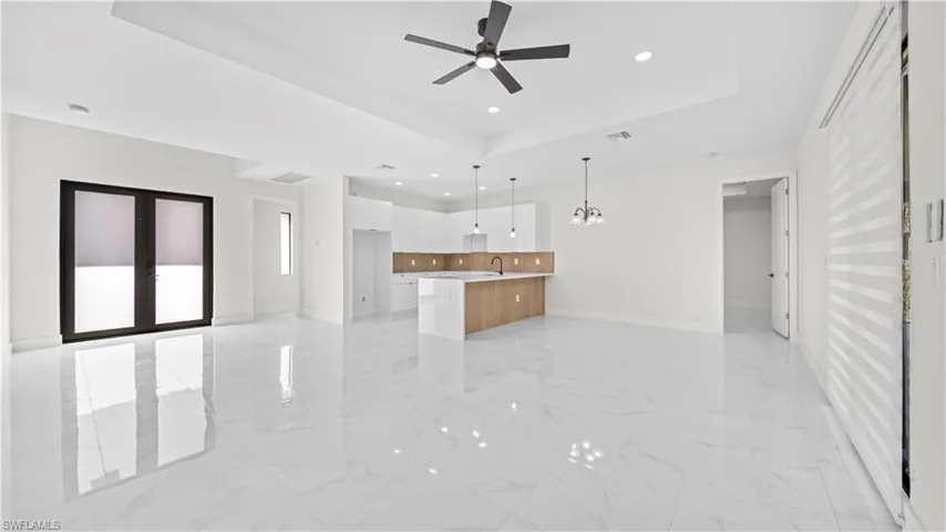 Kitchen featuring open floor plan, light countertops, white cabinets, a tray ceiling, and recessed lighting
