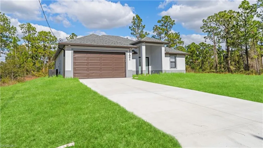 Prairie-style house featuring a front yard, a shingled roof, stucco siding, concrete driveway, and a garage