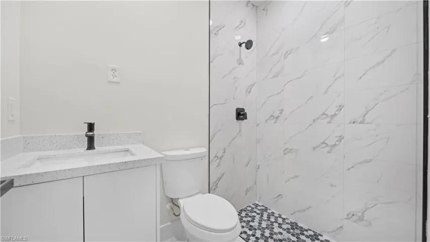 Bathroom with vanity and a marble finish shower