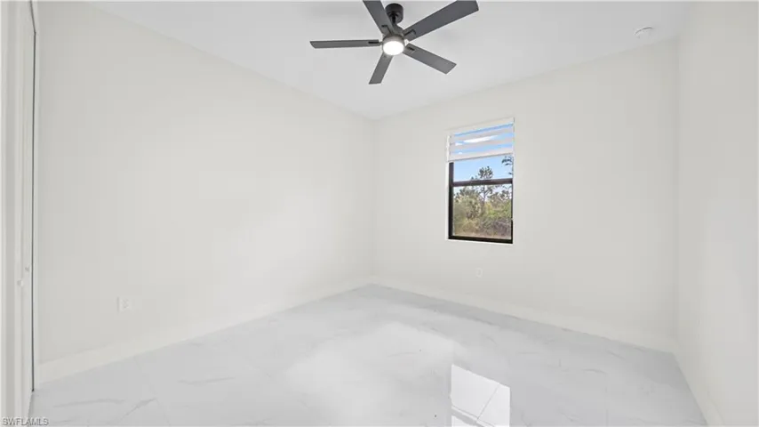 Unfurnished room featuring marble finish floors and ceiling fan