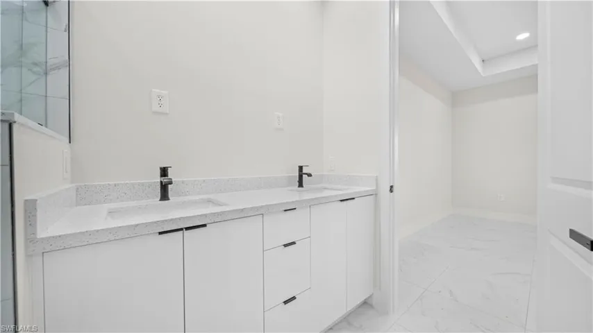 Bathroom with light marble finish flooring, double vanity, and recessed lighting