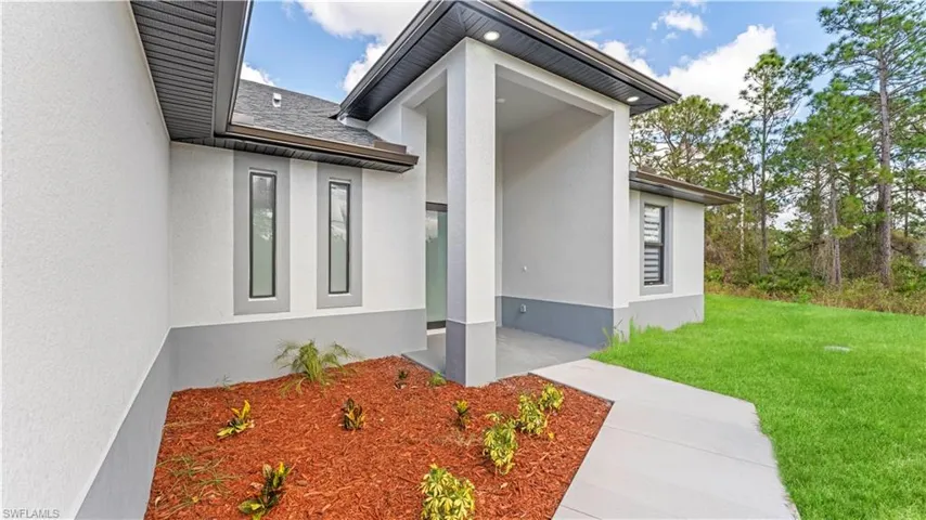 Doorway to property featuring a lawn and stucco siding