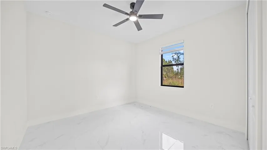 Unfurnished room with light marble finish flooring and ceiling fan