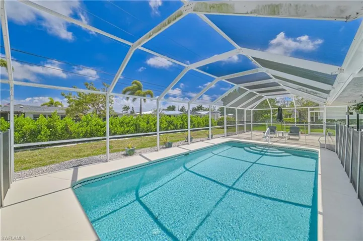 Outdoor pool featuring screened enclosure, a patio, a yard, and a sunroom