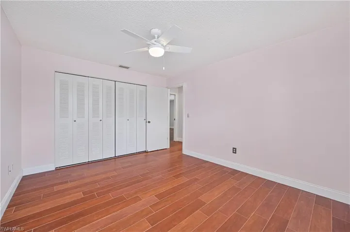 Unfurnished bedroom with wood look finished Tile floors, a ceiling fan, a textured ceiling, and a closet