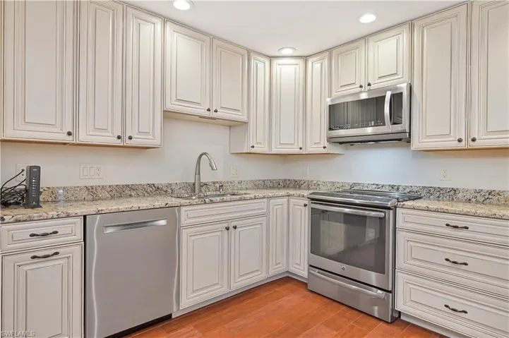 Kitchen with stainless steel appliances, Granite countertops, Tile flooring, recessed lighting, and cream cabinets