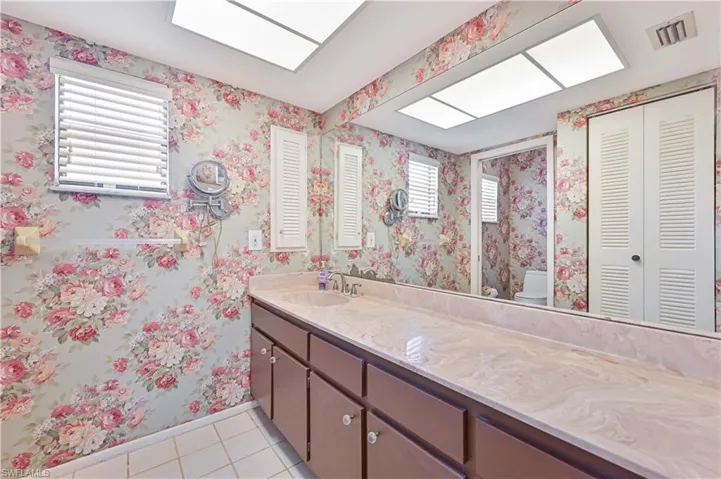 Bathroom featuring light tile patterned flooring, vanity, wallpapered walls, and a closet