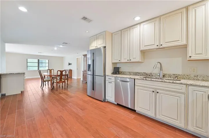 Kitchen featuring light stone counters, appliances with stainless steel finishes, recessed lighting, Tile finished floors, and cream cabinetry