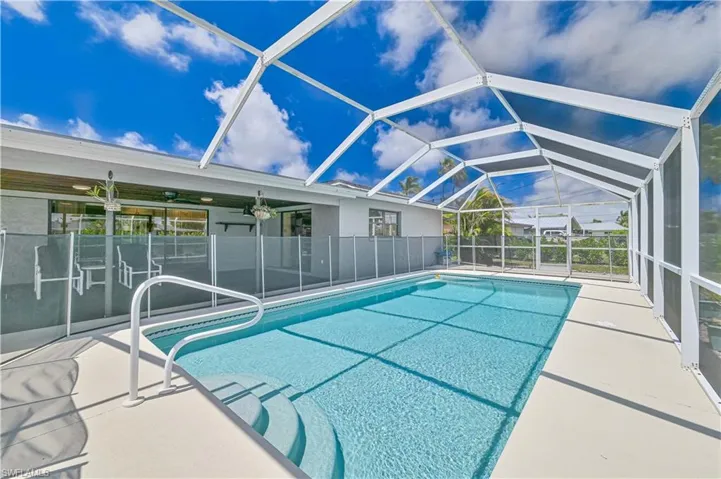 View of swimming pool with screened enclosure, a patio area, a sunroom, and a ceiling fan