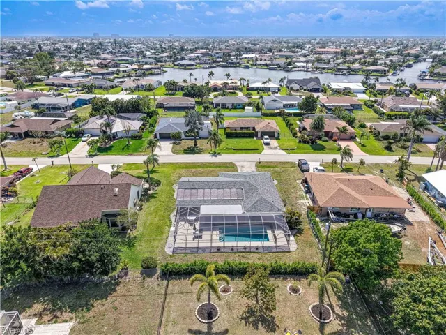 Aerial perspective of suburban area with a pool and a large body of water