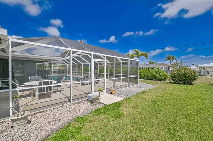 View of grassy yard with a lanai, an outdoor pool, a patio area, and a sunroom