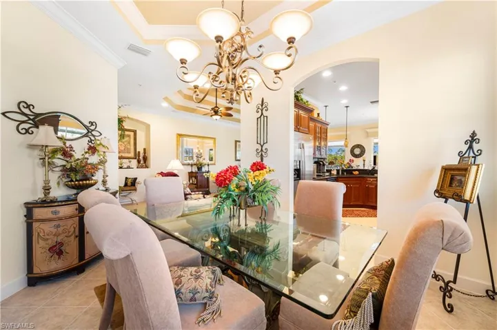 Dining space featuring light tile patterned floors, crown molding, arched walkways, a chandelier, and recessed lighting