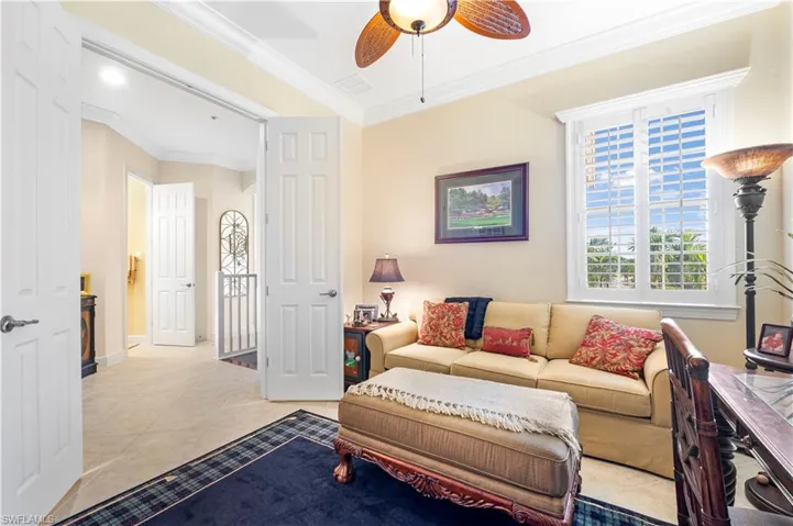 Tiled living area with crown molding and a ceiling fan
