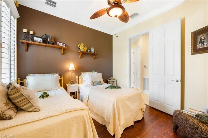 Bedroom with crown molding, wood finished floors, and ceiling fan