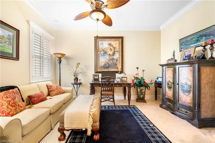 Living room featuring ornamental molding, light tile patterned floors, and a ceiling fan