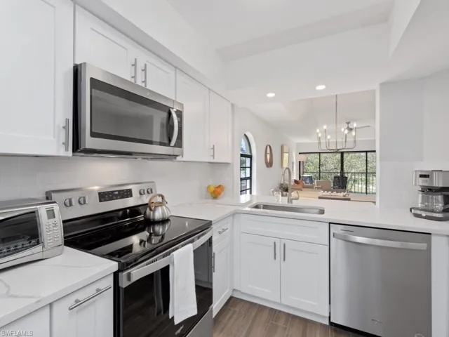 Kitchen featuring stainless steel appliances, white cabinets, tasteful backsplash, and sink