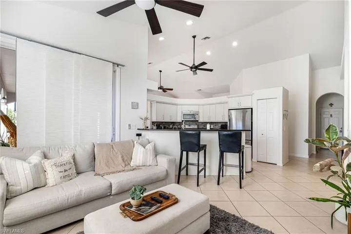 Living room with high vaulted ceiling, light tile patterned flooring, and arched walkways