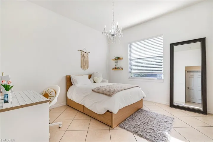 Bedroom with light tile patterned floors and a chandelier