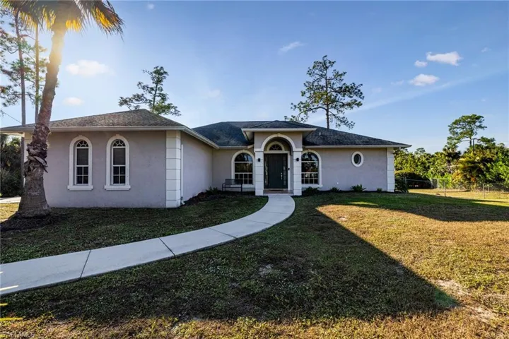 Ranch-style home with stucco siding, a front yard, and roof with shingles