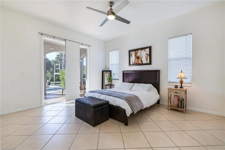 Bedroom featuring access to outside, multiple windows, light tile patterned floors, and a ceiling fan