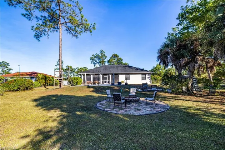 Rear view of house featuring a patio, a fire pit, a sunroom, and a yard