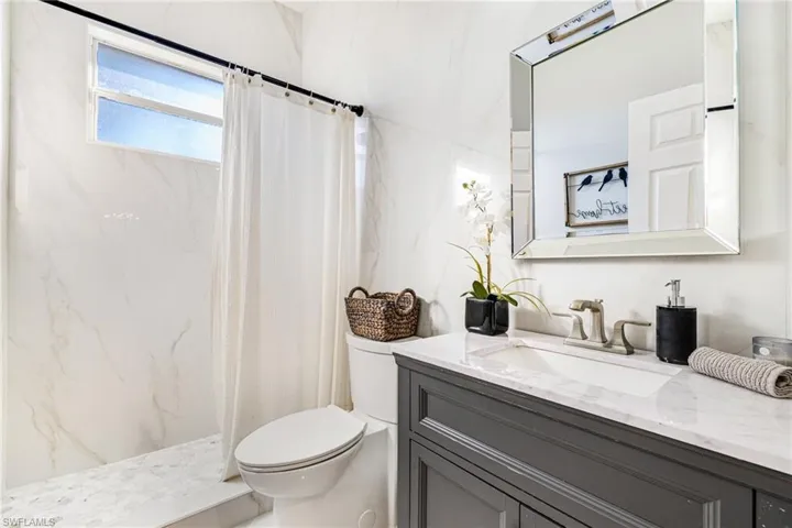 Full bathroom featuring a marble finish shower and vanity