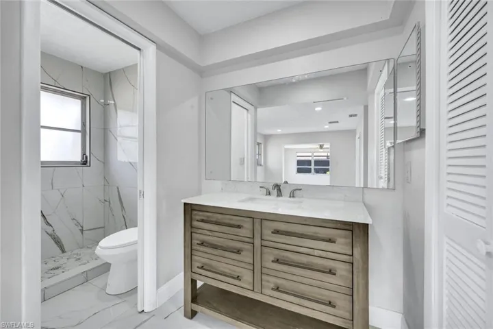 Full bathroom with baseboards, toilet, vanity, a marble finish shower, and marble finish floor