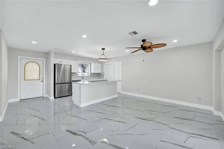 Unfurnished living room featuring marble finish floor, visible vents, and baseboards