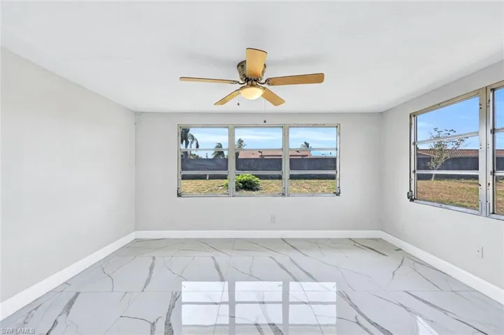 Unfurnished room with marble finish floor, baseboards, and a ceiling fan