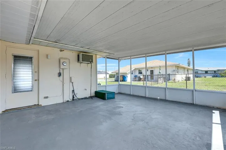 Unfurnished sunroom featuring a wall unit AC and a residential view