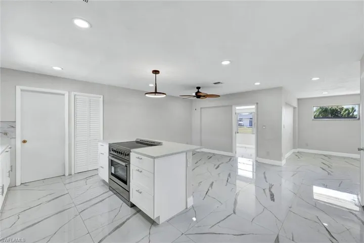 Kitchen with high end stove, white cabinetry, recessed lighting, marble finish floor, and light countertops