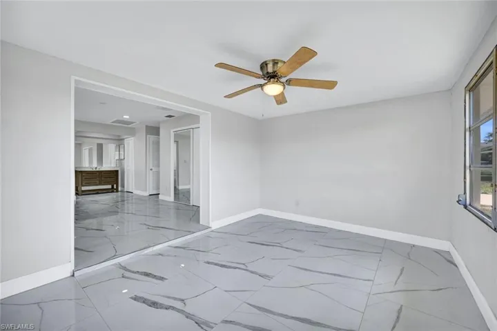 Empty room with baseboards, a ceiling fan, and marble finish floor