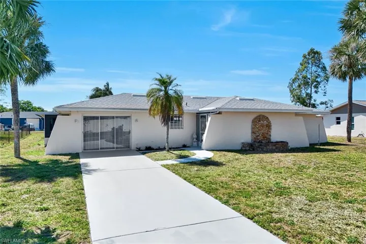 Ranch-style home featuring driveway, stucco siding, and a front yard