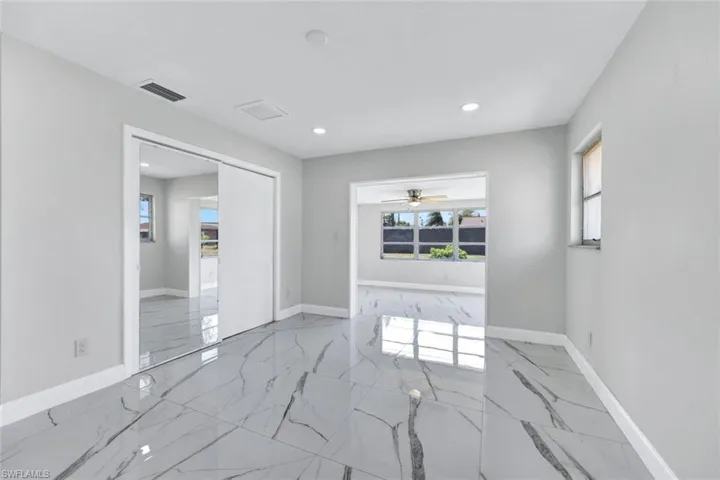 Unfurnished room featuring a wealth of natural light, visible vents, marble finish floor, and ceiling fan