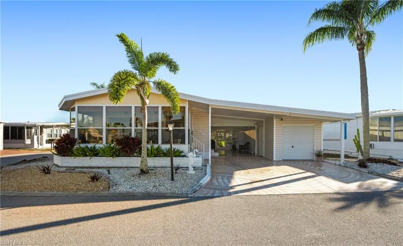 Manufactured / mobile home featuring a carport, a sunroom, concrete driveway, a garage, and a patio