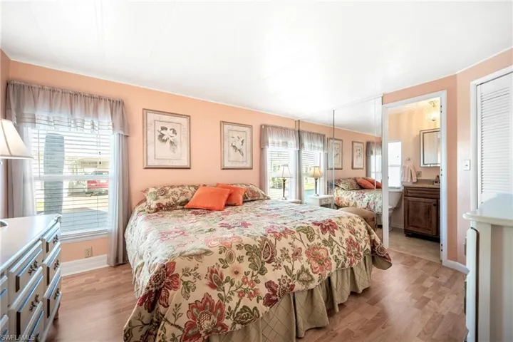 Bedroom featuring light wood-type flooring, ensuite bathroom, and multiple windows