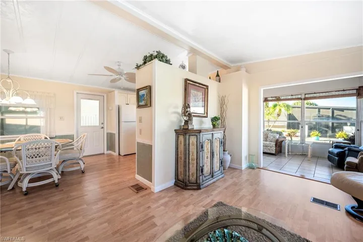 Living room featuring healthy amount of natural light, a ceiling fan, light wood-style flooring, crown molding, and a chandelier
