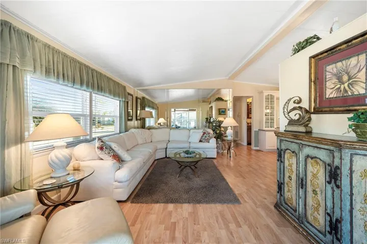 Living area with lofted ceiling, light wood finished floors, and healthy amount of natural light