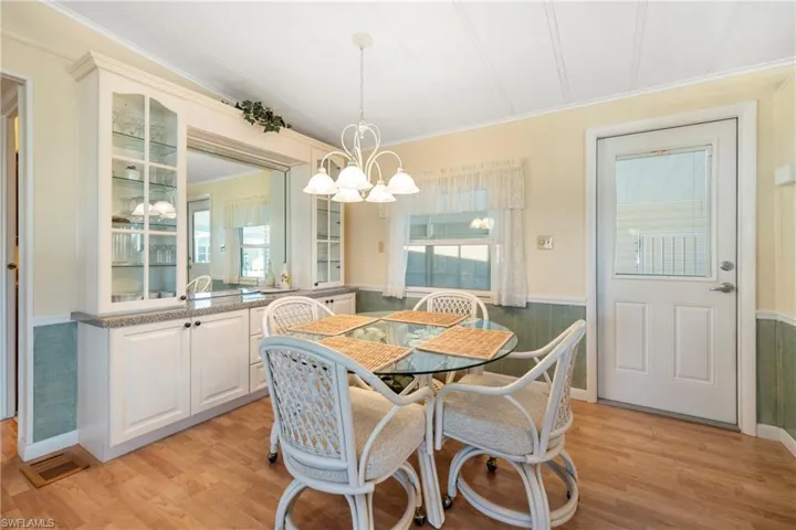 Dining space with wainscoting, light wood-type flooring, ornamental molding, and a chandelier
