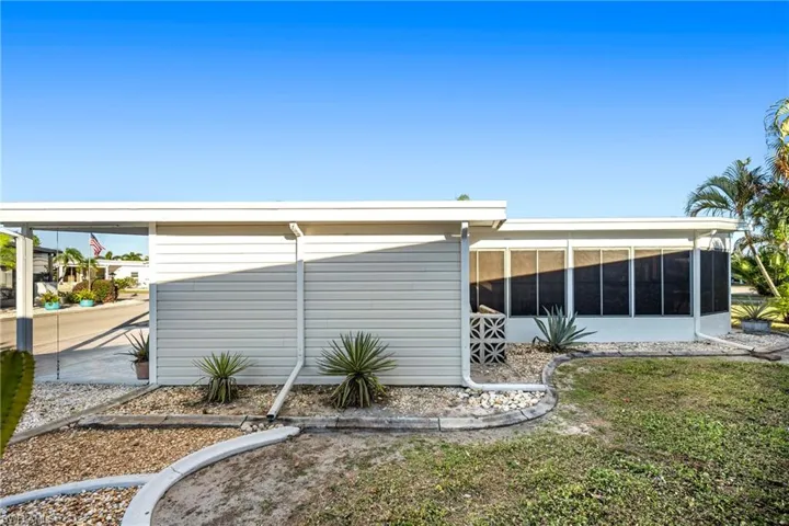 View of side of property featuring a sunroom and a lawn