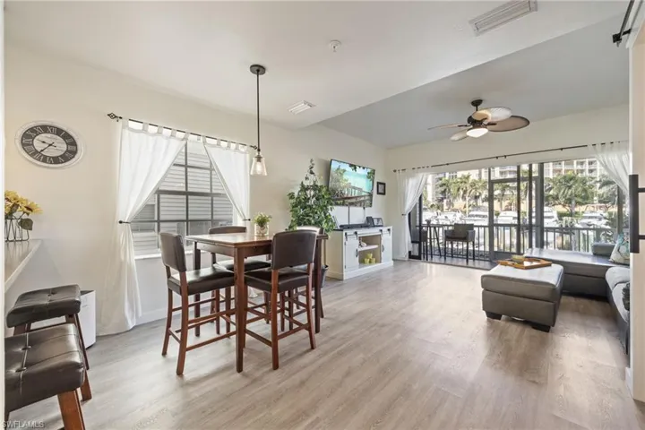 Spacious open-concept living area featuring light wood-finish flooring and a glass-paneled sliding door leading to an outdoor balcony