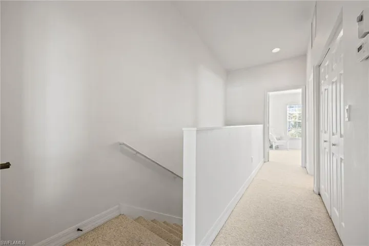 Upper-level hallway featuring light-toned carpeting, white walls, and recessed lighting