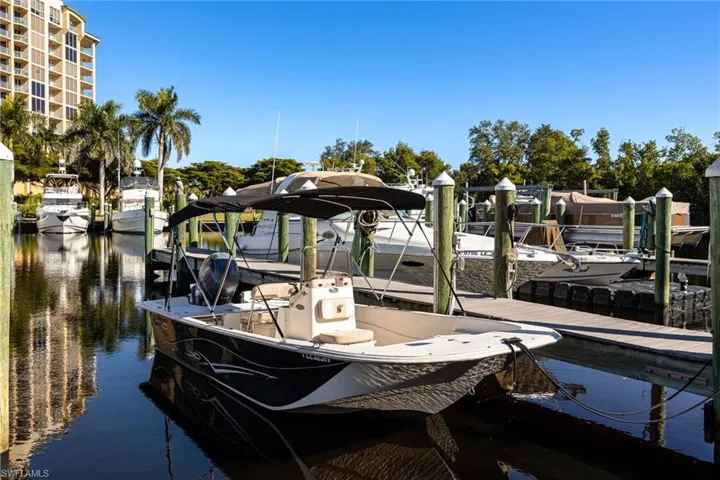 Waterfront property featuring dock access, boat slips, a multi-story building, and mature palm trees