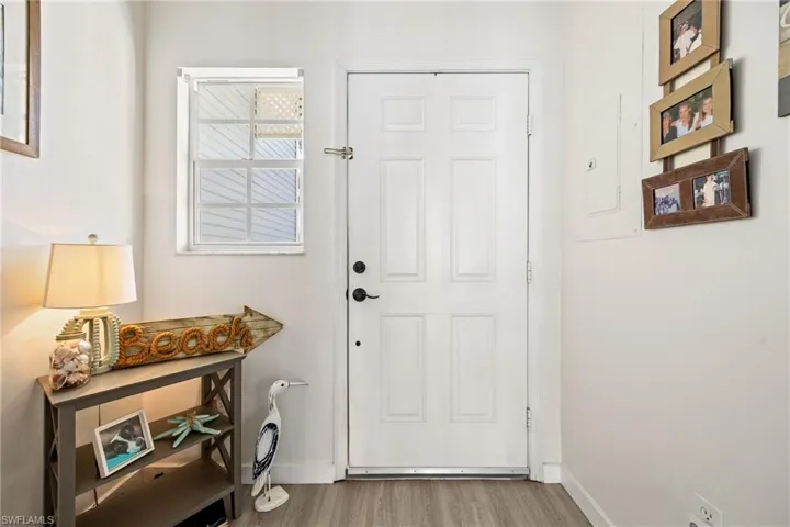 Entryway featuring a white paneled door, light wood-finish flooring, and a window with horizontal blinds