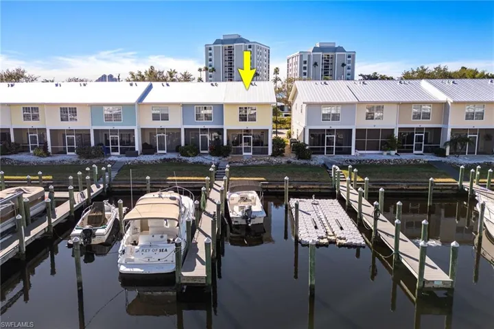 Waterfront townhome featuring a metal roof, screened patio, and a private boat dock with pilings